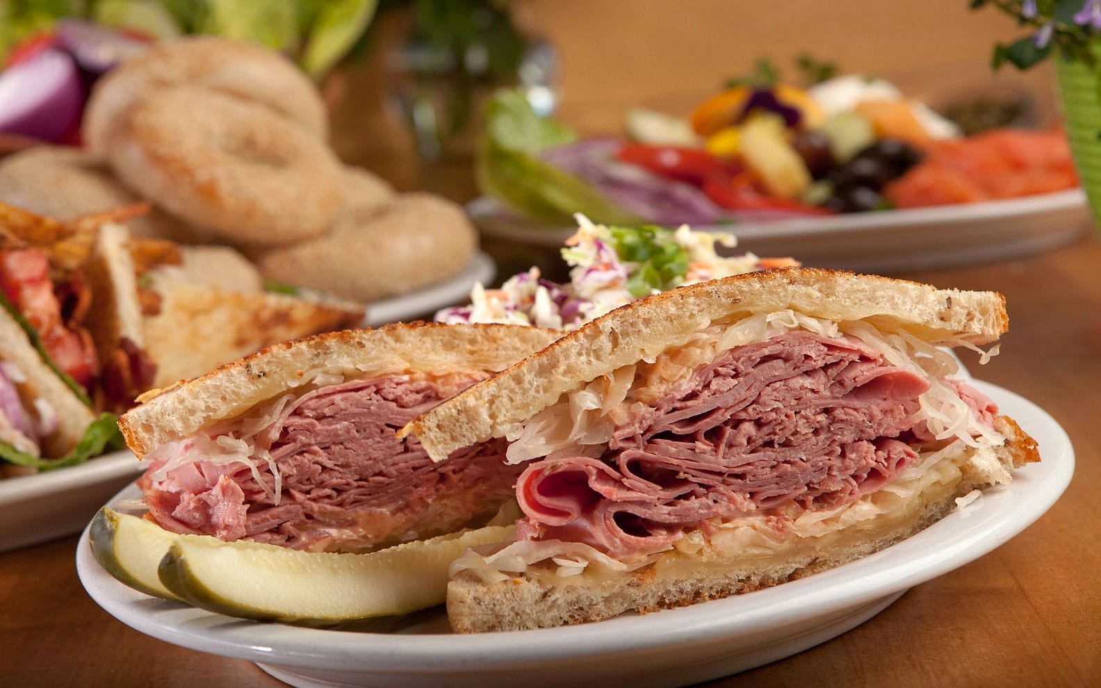 A stacked corned beef sandwich on grilled rye with sauerkraut, with more plates from the Brothers' kitchen behind